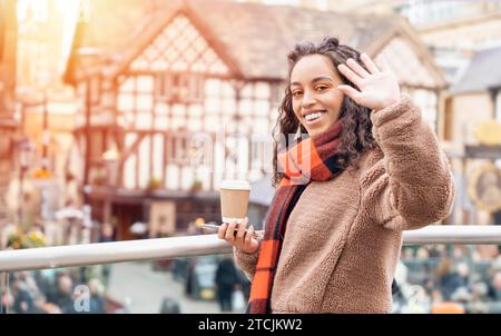 Femme joyeuse saluant quelqu'un et rencontrant des amis dans une ville d'Europe Banque D'Images