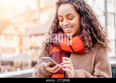 Portrait en plein air d'une femme heureuse parlant au téléphone dans une ville en Angleterre Banque D'Images