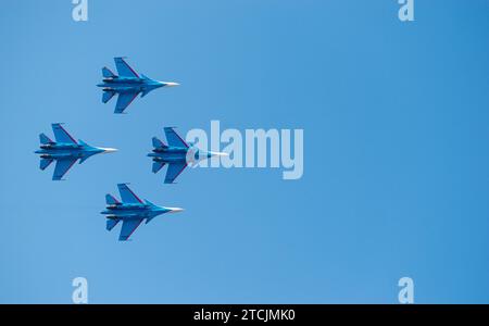 Quatre avions de chasse Sukhoi su-27 Flanker de l'armée de l'air russe volent dans une formation à couper le souffle contre un ciel bleu clair. Banque D'Images