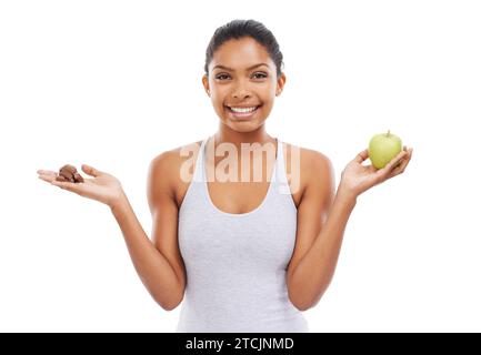 Pomme, chocolat et femme pour un choix alimentaire sain ou offrir avec de la nourriture, du sucre et un régime alimentaire sur fond blanc. Portrait de jeune personne heureuse avec le vert Banque D'Images