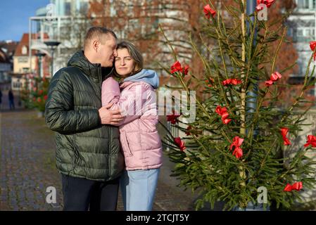 Portrait de jeunes gens attrayants, couple charmant bénéficiant de l'atmosphère chaleureuse sur la foire dans la veille de Noël. Passer du temps ensemble. Concept de trad nationale Banque D'Images