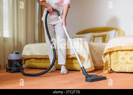 Image rapprochée de la chambre de la femme de ménage de l'hôtel qui passe l'aspirateur. Banque D'Images