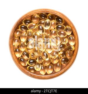 Capsules de gel souples dans un bol en bois. Médicament posologique oral ou complément alimentaire sous forme de capsule transparente. Banque D'Images