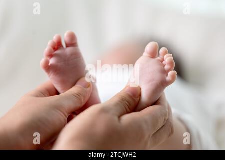 Les mains de la mère massant les pieds du nouveau-né Banque D'Images