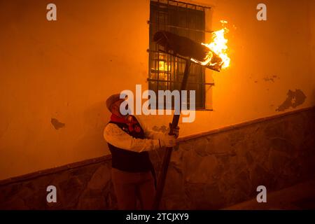 Un villageois tient une torche alors qu'il participe à la célébration de la procession de la Vierge Divina Pastora. À la veille de la fête de Santa Lucia dans le petit village de Casarabonela, les villageois prennent part à l'ancienne célébration de 'Los Rondeles' tous les soirs du 12 décembre pendant la période de Noël, portant des paniers en osier brûlants (également connus sous le nom de 'rondeles') trempés dans l'huile. Dans les rues, la Vierge de Los Rondeles est honorée par les fidèles dans un rituel de lumière et de feu en remerciement pour la moisson. Banque D'Images