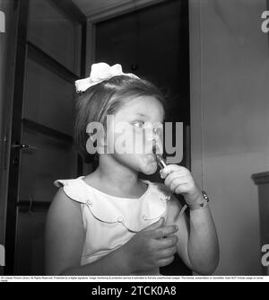 Dans les années 1950 Une petite fille se maquille, en utilisant un rouge à lèvres comme elle a vu sa mère le faire. 1956. Kristoffersson réf. BS95-1 Banque D'Images