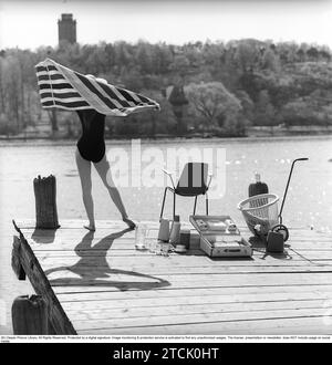 style de vie des années 1950. Une jeune femme au soleil portant un maillot de bain. Dans l'image, il y a beaucoup d'objets opportuns en plastique qui étaient populaires à l'époque. Surtout lorsque vous êtes en vacances d'été ou en camping. Un cas pratique pour les transporter. 1958 Kristoffersson réf DB96-1 Banque D'Images