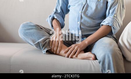 Femme enceinte méconnaissable à la maison massant son pied enflé Banque D'Images