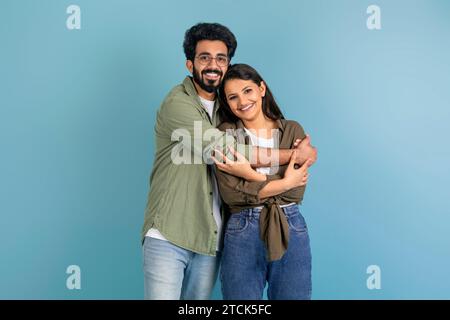 Portrait d'heureux jeune couple indien embrassant sur bleu Banque D'Images