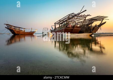 Des teintes dorées peignent le paisible bord de mer de Dammam tandis que les bateaux se reposent contre la lueur du matin, une étreinte sereine de la beauté de la nature en Arabie Saoudite. Banque D'Images