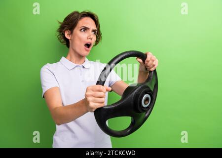 Photo de jeune fille en colère stupeur regardant la situation du crime sur la route conduisant l'automobile au volant isolé sur fond de couleur verte Banque D'Images