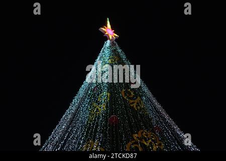 Arbre de Noël festif illuminé avec des lumières scintillantes sur un fond noir Banque D'Images