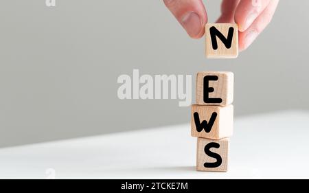 Fermer la main de jeune femme dans le cube bloc en bois chemise blanche pour les NOUVELLES mots sur le plancher de table blanc, clavier blanc sur le fond. financier Banque D'Images