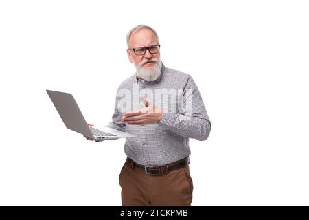 homme de bureau mature aux cheveux gris réussi avec une moustache et une barbe habillée d'un pantalon et une chemise tient un ordinateur portable Banque D'Images