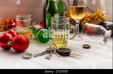 Un concept de conduite de Noël et de fête avec un jeu de clés de voiture sur une table pleine de boissons alcoolisées et de décorations. Banque D'Images