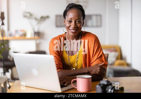 Smiling woman working on laptop at home Banque D'Images