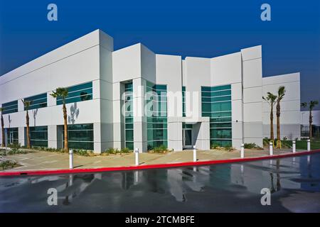 L'invention concerne un bâtiment de construction basculant vers le haut, contrôlé en perspective, situé dans un parc d'activités. Photographié avec un parking humide. Banque D'Images