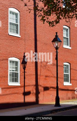 Ombre d'une lampe à gaz sur un mur peint en rouge sur Frederick Street dans le quartier historique de Fredericksburg Virginia Banque D'Images