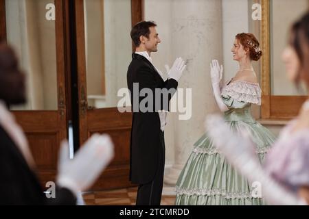 Portrait vue de côté d'une jeune femme et d'un homme profitant de danses volantes dans la salle de bal du palais, espace copie Banque D'Images