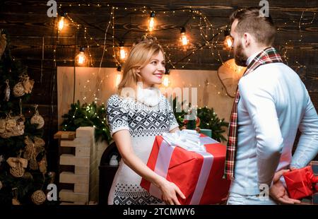 Couple aimant ravi positif se donnant des cadeaux de Noël. Fêter Noël ensemble. Vacances d'hiver en famille et concept de personnes Banque D'Images