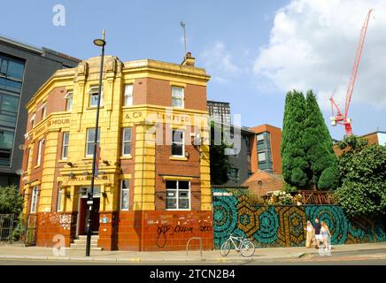 Une vue extérieure du Rutland Arms, un bâtiment en briques orange et jaune vif dans le centre de Sheffield. Les jeunes passent. Banque D'Images