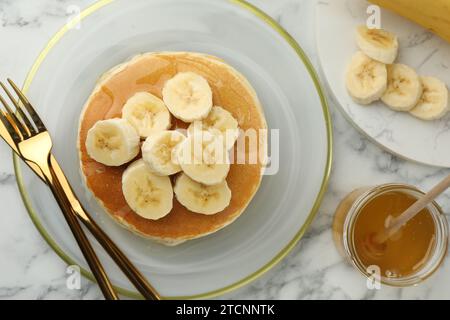 Délicieuses crêpes aux bananes et au miel servies sur une table en marbre blanc, à plat Banque D'Images