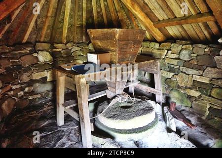 À l'intérieur du moulin nordique historique sur Lewis Island, en Écosse. Les murs rustiques en pierre et les chevrons en bois protègent les meules et la trémie à grain Banque D'Images