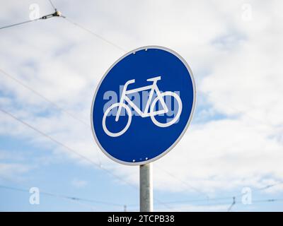 Panneau de piste cyclable de près en Allemagne. Le vélo blanc est sur un sol bleu. La forme du symbole est ronde. Guidage pour les différents usagers de la route. Banque D'Images
