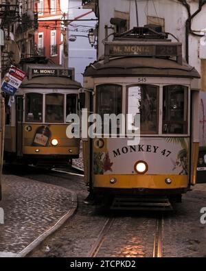 Tramways vintage de la ligne 28 voyageant dans la rue étroite dans le quartier Alfama de Lisbonne à Dusk, Portugal Europe Banque D'Images