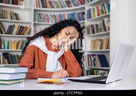 Étudiante fille fatiguée s'est endormie en étudiant assise à la table devant l'ordinateur portable, fatiguée d'étudier, burnout. Banque D'Images