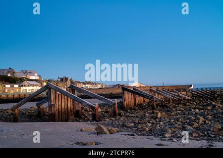 Lumière glaciale de lever de soleil d'hiver sur les groynes sur East Beach. Lossiemouth, Morayshire, Écosse Banque D'Images