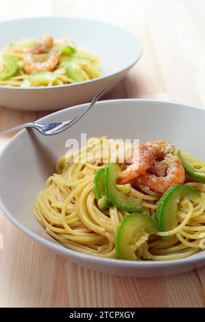 Pâtes spaghetti avec crevettes fraîches et sauce courgettes sur table en bois Banque D'Images