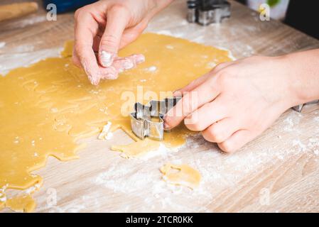 Pâte découpant la pâte pour les biscuits. Main dans la main Banque D'Images
