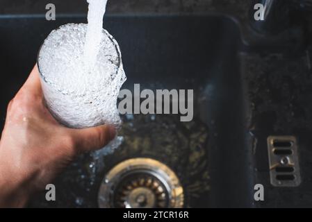 Verre de remplissage de l'eau du robinet de cuisine en acier inoxydable. Concept d'eau potable. Autriche eau pure des montagnes Banque D'Images