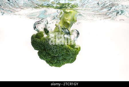 Gros plan de brocoli éclabousse dans l'eau isolée sur blanc. Concept d'alimentation saine Banque D'Images