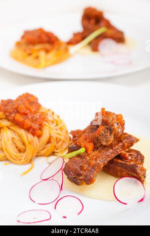 Pâtes spaghetti italiennes traditionnelles avec sauce aux côtes de porc servies sur lit de polenta Banque D'Images