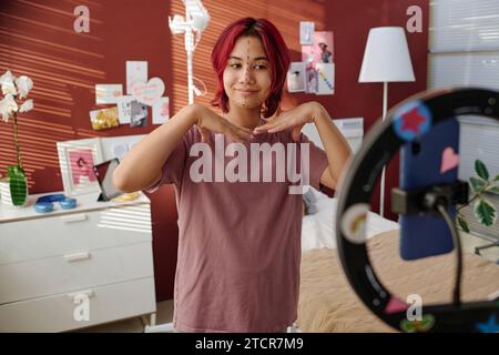 Jeune fille souriante avec des marques de liftmark sur son visage faisant livestream pour les abonnés devant la caméra smartphone dans le service d'hôpital Banque D'Images