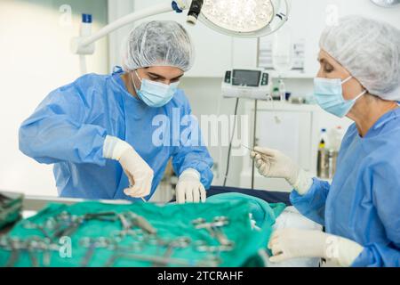 Jeune vétérinaire avec assistante féminine effectuant une opération chirurgicale à la clinique vétérinaire Banque D'Images