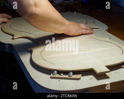 Artisan luthier fabricant d'instruments à cordes sculpte une plaque arrière de violoncelle en bois d'épicéa avec gouge à Crémone Italie Banque D'Images