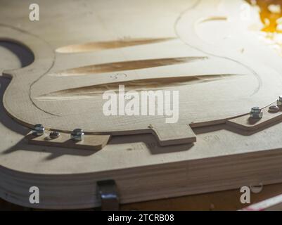 Artisan luthier fabricant d'instruments à cordes sculpte une plaque arrière de violoncelle en bois d'épicéa avec gouge à Crémone Italie Banque D'Images