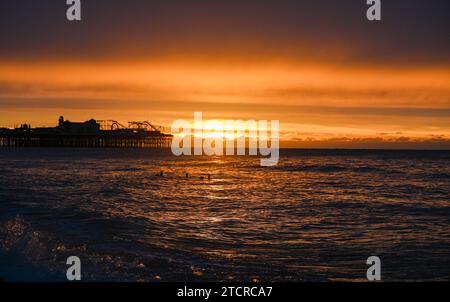 Brighton Royaume-Uni 14 décembre 2023 - les nageurs tôt le matin attrapent le lever du soleil à Brighton par un matin froid le long de la côte sud . Les nageurs sont membres de iSWIM qui est une communauté de nageurs de mer basée à Brighton & Hove, affiliée au Brighton Sailing Club : Credit Simon Dack / Alamy Live News Banque D'Images