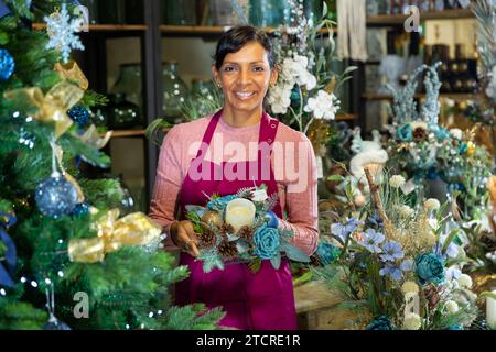 Portrait d'une femme vendeur tenant une composition de Noël avec des bougies Banque D'Images