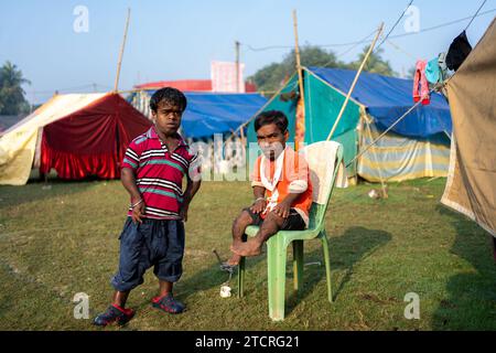 Kolkata, Inde. 14 décembre 2023. Deux hommes nains, qui jouent le rôle de joker dans un cirque, sont vus devant leurs tentes dans un sol où ils vivent pendant la saison hivernale. L'hiver et l'enfance signifiaient une époque où il y avait une attraction et un amour distincts pour le cirque. Mais maintenant, les temps ont changé de sorte que la demande a également diminué, surtout après que le spectacle de tout type d'animaux dans le cirque a cessé, les propriétaires des équipes de cirque sont plus contrariés. Maintenant, le jeu est montré seulement avec des jokers ou des gens. Et en conséquence, le revenu a diminué. Crédit : SOPA Images Limited/Alamy Live News Banque D'Images