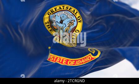 Gros plan du drapeau de l'État de l'Idaho brandissant par temps clair. Sceau d'État dans une zone bleu foncé avec les mots State of Idaho en lettres dorées sur une bande sous le s. Banque D'Images