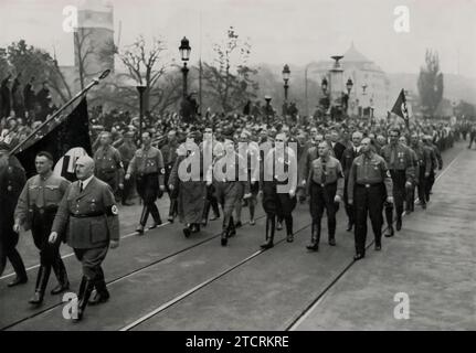 Le 9 novembre 1934, la reconstitution de la marche historique commémore un moment charnière de l'histoire nazie. Cet événement, qui a lieu chaque année, marque l'anniversaire du putsch de la brasserie de 1923, une tentative ratée de coup d'État qui a joué un rôle crucial dans la montée du parti nazi. La marche symbolise l'accent mis par le régime sur la tradition et la glorification de ses premières luttes, renforçant le récit de la persévérance et du triomphe éventuel. Banque D'Images