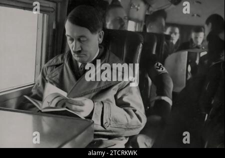 Adolf Hitler est représenté assis dans les limites d'un avion, un moment capturant son implication directe dans les aspects opérationnels de son leadership. L'image traduit son approche dynamique de la gouvernance, utilisant les transports modernes pour superviser et diriger les activités du régime nazi. Cette représentation souligne l'importance accordée à l'avancement technologique et à la mobilité, présentant Hitler comme un leader activement engagé pendant une période critique de l'histoire. » Banque D'Images