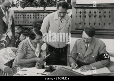 Adolf Hitler est montré pendant l'été lors de sa retraite d'Obersalzberg, un cadre souvent utilisé pour le dépeindre sous un jour plus détendu et informel. Cette image, capturant un moment estival, est probablement destinée à humaniser Hitler et à présenter un contraste avec ses apparences plus formelles et politiques. Banque D'Images