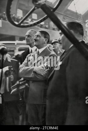 1935 salon international de l'automobile à Berlin, Adolf Hitler est représenté dans son rôle de patron de l'industrie automobile, soulignant le soutien du régime à un secteur clé. Sa présence à un événement aussi important souligne l’importance accordée à l’industrie automobile dans l’Allemagne nazie, tant pour son impact économique que pour son rôle dans la mise en valeur de l’innovation technologique allemande. L'exposition, présentant les dernières avancées en matière de technologie automobile, était une plate-forme idéale pour Hitler pour souligner l'engagement du régime envers le progrès industriel et le prestige national dans la fabrication de véhicules. Banque D'Images