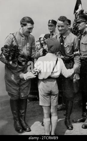 Adolf Hitler reçoit un accueil enthousiaste de la part de jeunes partisans lors d'une campagne électorale, comme le montre la jeune Allemagne salue le Führer dans la campagne électorale. Cette image souligne le soutien significatif que Hitler avait parmi la jeunesse, un facteur vital dans son ascension au pouvoir. La scène du salut fervent de la jeune génération illustre le succès du régime nazi dans la mobilisation et l'endoctrinement de la jeunesse, élément crucial dans la diffusion de son idéologie et la consolidation de sa base de soutien Banque D'Images