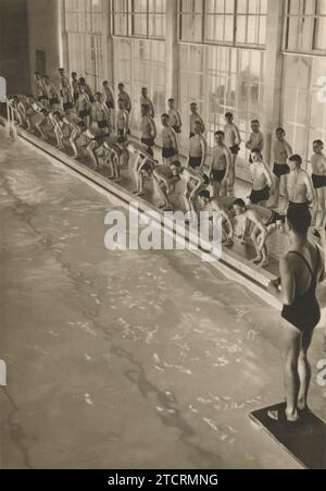 Les nouvelles recrues en formation militaire allemande sont montrées lors de leur séance sportive matinale, qui implique à cette occasion de nager. Cette activité rigoureuse fait partie de leur formation complète, les préparant probablement au service dans la Marine (Kriegsmarine). L'accent mis sur la natation met l'accent sur l'importance de la condition physique et des compétences spécialisées requises pour les opérations navales. Banque D'Images